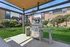 Inviting communal area featuring a sleek stainless steel grill under a wooden pergola, surrounded by well-maintained apartments and lush green landscaping.