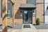 Charming brick entryway with modern glass doors, framed by rustic wooden beams in a welcoming residential building.