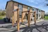Charming brick leasing office with wooden entry beams and manicured landscaping, set against a clear blue sky.
