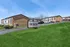 Charming apartment complex with modern signage and lush green landscaping under a clear blue sky, promising comfortable living in a serene environment.