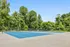 Sunny, spacious tennis court surrounded by lush greenery, perfect for outdoor recreation.