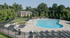 Inviting apartment complex with a spacious outdoor pool, surrounded by lush greenery and ample lounge seating for relaxation.