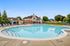 Inviting outdoor pool with lounge chairs and scenic clubhouse, set against a backdrop of lush greenery and clear blue skies.