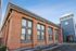 Charming apartment building with historic brick facade and modern clock tower, featuring large windows for abundant natural light.