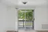 Bright and airy room with floor-to-ceiling glass doors leading to a private balcony, offering a serene view of lush greenery.