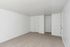 Bright and spacious room with fresh white walls, plush carpet flooring, and two neatly paneled doors creating a modern minimalist appeal.