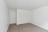 Bright, spacious bedroom with plush carpet and modern white closet doors, offering a blank canvas for personalization.