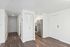 Modern apartment entrance with sleek hardwood flooring and stainless steel appliances in view.