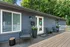 Charming apartment entrance with cozy seating, modern siding, and lush greenery.