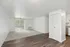 Bright, modern living space with sleek hardwood floors, cozy carpet area, and large sliding glass doors leading to a private balcony.