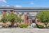 Charming brick apartment building with lush greenery and inviting entryway under a bright blue sky.
