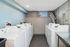 Bright and modern laundry room with multiple white washing machines, sleek design, and ample natural light.