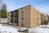 Charming three-story brick apartment building with modern balconies nestled in a serene snow-kissed landscape.