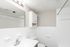 Bright and modern bathroom featuring a sleek white vanity, large mirror, and ample storage space with a stylish cabinet.