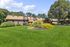 Beautiful apartment complex showcasing well-maintained gardens, vibrant landscaping, and charming brick architecture under a clear blue sky.