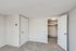 Bright and airy modern room with soft carpet flooring and a convenient walk-in closet, showcasing minimalist elegance.