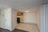 Cozy apartment space featuring a modern kitchen with wooden cabinets opening into a bright living area with tiled flooring.