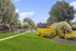 Serene apartment community showcasing vibrant gardens, a sparkling pool, and lush greenery under a clear blue sky.