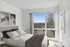 Bright bedroom with modern decor, large window offering scenic city views, and elegant wall art.