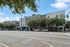 Modern apartment complex with sleek design, tree-lined street, and ample parking in a vibrant urban setting.