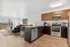 Modern open-plan kitchen and living area featuring sleek stainless steel appliances, elegant wood cabinetry, and large windows with a scenic view.