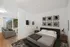 Modern bedroom with a stylish bed and artistic wall decor, adjacent to a cozy living area with a large sliding door leading to an outdoor view.