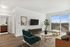 Bright and modern living room with elegant furniture, a wall-mounted TV, and a large window offering a stunning view.