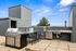 Modern rooftop terrace with sleek stainless steel BBQ grill, outdoor sink, and bar seating, ideal for entertaining under a clear blue sky.