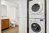Modern bathroom with elegant wooden vanity beside a convenient stacked washer and dryer unit, offering seamless functionality for stylish urban living.