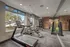 Modern fitness center with large windows, featuring a treadmill, elliptical, weight machines, and vibrant exercise balls.