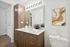 Elegant bathroom featuring modern wood cabinetry, large mirror with stylish lighting, and contemporary art decor.