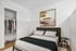 Chic bedroom with a cozy bed, modern artwork, and spacious closet, perfect for stylish living.