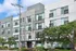 Modern four-story apartment building with stylish facade, lush landscaping, and convenient leasing office access.