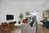 Chic living area with modern sofas, a sleek TV setup, and large windows offering abundant natural light and a view of the neighborhood.