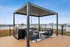 Modern rooftop terrace with elegant pergola, comfortable seating area, and stainless steel barbecue grill, offering stunning views.