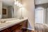 Elegant modern bathroom featuring dual sinks with stylish fixtures, ample wooden cabinetry, and a spacious layout.