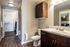 Modern bathroom with sleek dark wood cabinetry, elegant sink, and inviting bathtub accessed through a spacious walk-in closet.