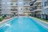 Modern apartment complex with a refreshing outdoor pool, surrounded by lounge chairs and stylish balconies.