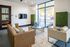Modern apartment lounge with chic leather sofas, flat-screen TV, and floor-to-ceiling windows for abundant natural light.