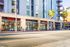 Modern urban apartment building with convenient street-level retail shops, including CVS Pharmacy, framed by lush palm trees.