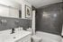Modern bathroom featuring sleek grey tiles, white fixtures, and stylish wall art.