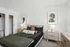 Elegant bedroom with modern decor, featuring a plush bed, stylish side tables, and artistic wall portraits.
