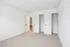 Bright and spacious bedroom with plush carpeting, featuring double closet space and a modern minimalist design.