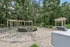 Charming outdoor patio featuring elegant pergolas, cozy circular seating around a fire pit, and lush green surroundings.