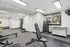 Bright and modern fitness room featuring state-of-the-art rowing machine, adjustable bench, and a rack of dumbbells. Large window provides natural light and outdoor view.