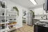 Modern kitchen with sleek stainless steel appliances, elegant white cabinetry, and open shelving adorned with greenery.