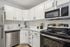 Modern kitchen with sleek white cabinetry, stainless steel appliances, and marble countertops.