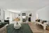 Elegant open-concept living space with stylish decor, featuring a cozy sitting area, chic dining table, and modern kitchen entrance, all bathed in natural light.