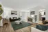 Modern open living space with a plush green sofa, stylish decor, and sleek kitchen in a bright apartment.