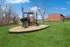 Inviting playground in a serene apartment community setting, surrounded by lush green lawns and charming brick buildings.